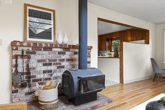 room details featuring a textured ceiling, a wood stove, baseboards, and wood finished floors