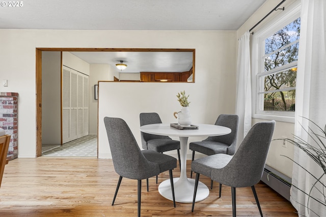 dining room with light wood-type flooring and baseboard heating