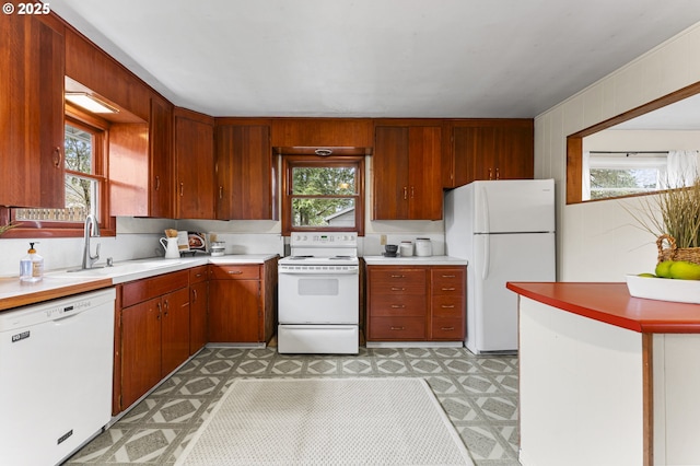 kitchen with light floors, white appliances, a healthy amount of sunlight, and a sink