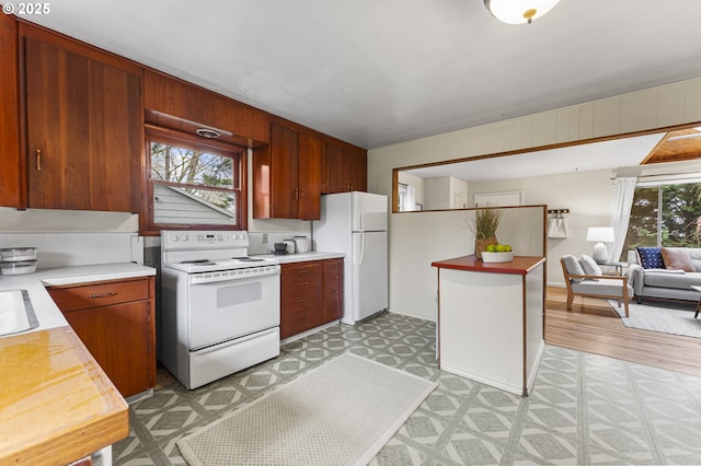 kitchen featuring a sink, open floor plan, white appliances, light countertops, and light floors