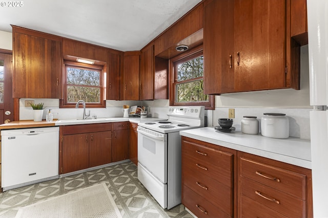 kitchen featuring white appliances, light floors, light countertops, and a sink