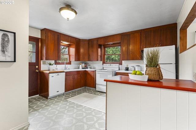 kitchen with a wealth of natural light, light floors, white appliances, and a sink