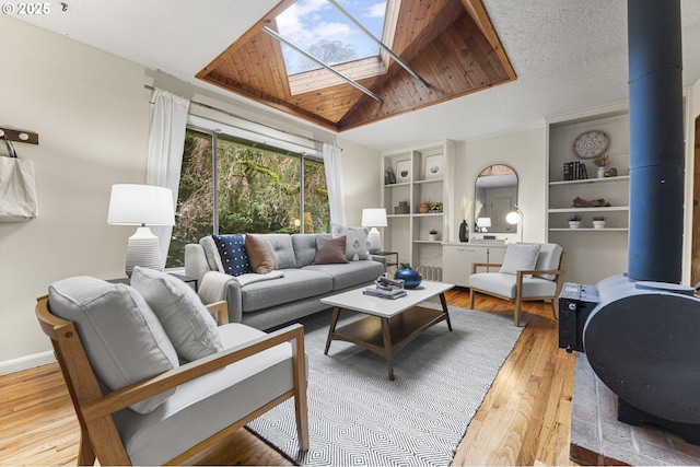 living room featuring hardwood / wood-style floors, baseboards, a wood stove, a textured ceiling, and lofted ceiling with skylight