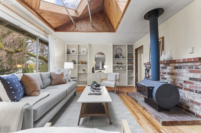 living area featuring a skylight, a textured ceiling, wood finished floors, and a wood stove