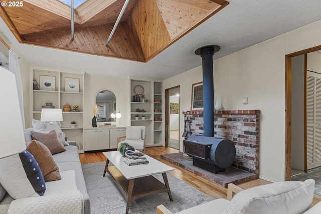 living area featuring wood finished floors, a wood stove, a skylight, a textured ceiling, and wooden ceiling