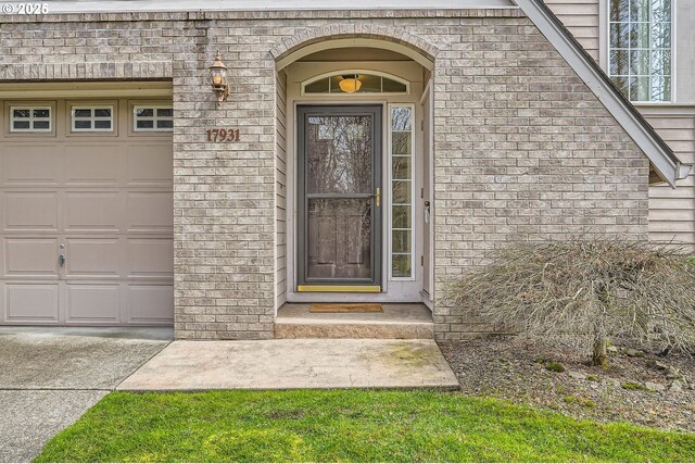 property entrance with a garage and brick siding