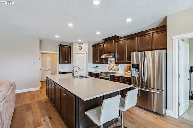 4905 S 12th Cir, Ridgefield, WA 98642 - kitchen with appliances with stainless steel finishes, under cabinet range hood, light wood-style floors, dark brown cabinets, and light countertops