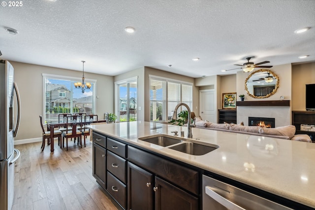 4905 S 12th Cir, Ridgefield, WA 98642 - kitchen featuring stainless steel appliances, a textured ceiling, a fireplace, light wood-style floors, and light countertops