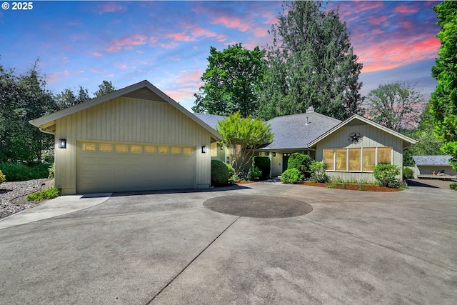 ranch-style home with driveway, an attached garage, a chimney, and roof with shingles