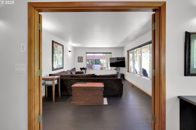 living area with dark wood-type flooring and baseboards