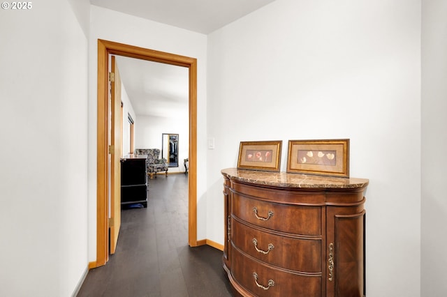 corridor featuring dark wood finished floors and baseboards