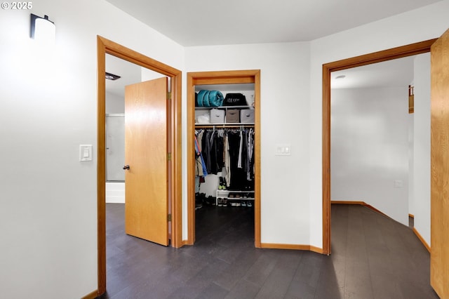 hall with dark wood-style flooring and baseboards