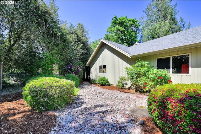 view of side of home with roof with shingles
