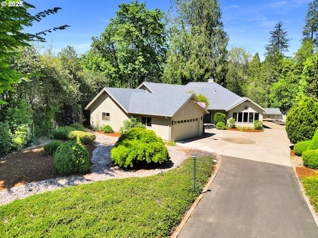 ranch-style house featuring an attached garage, concrete driveway, a chimney, and a shingled roof
