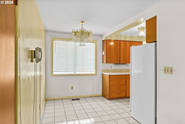 kitchen with visible vents, baseboards, freestanding refrigerator, a chandelier, and light countertops