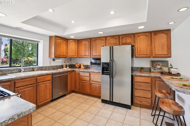 2027 SE Lexington St, Portland, OR 97202 - kitchen with stainless steel appliances, a tray ceiling, brown cabinets, recessed lighting, and light tile patterned floors