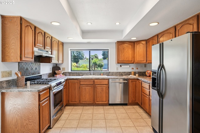 2027 SE Lexington St, Portland, OR 97202 - kitchen featuring appliances with stainless steel finishes, under cabinet range hood, brown cabinetry, recessed lighting, and light tile patterned floors