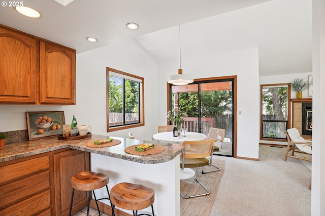 2027 SE Lexington St, Portland, OR 97202 - kitchen featuring brown cabinetry, plenty of natural light, a kitchen bar, vaulted ceiling, and recessed lighting