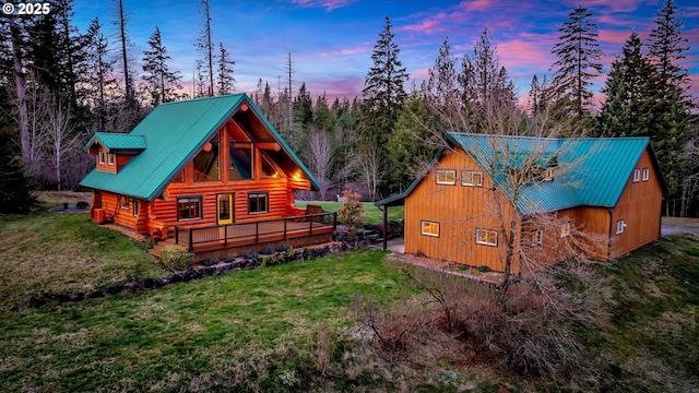 property exterior at dusk with a lawn and a wooden deck