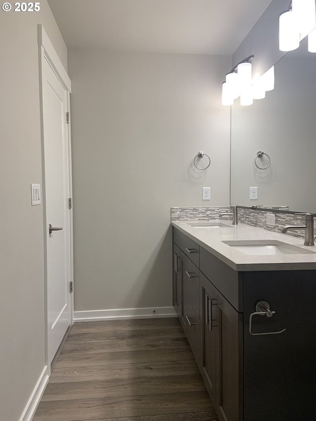 bathroom with a sink, baseboards, double vanity, and wood finished floors