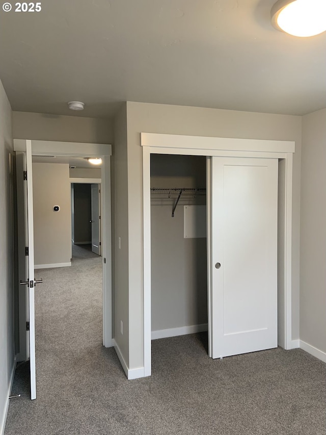 unfurnished bedroom with carpet floors, baseboards, and a closet