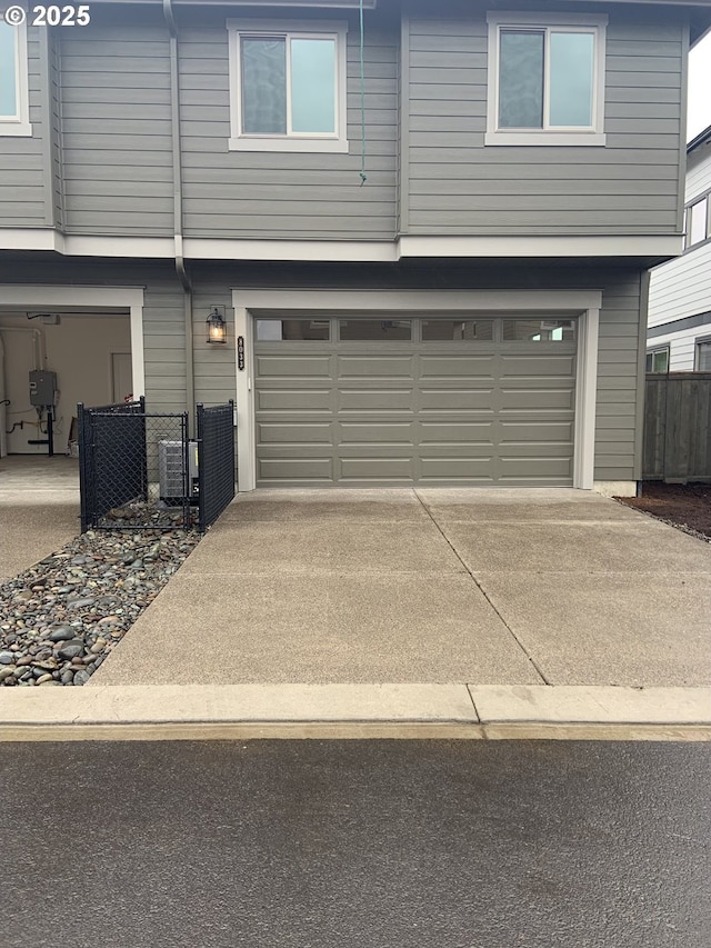 garage featuring fence, cooling unit, and driveway