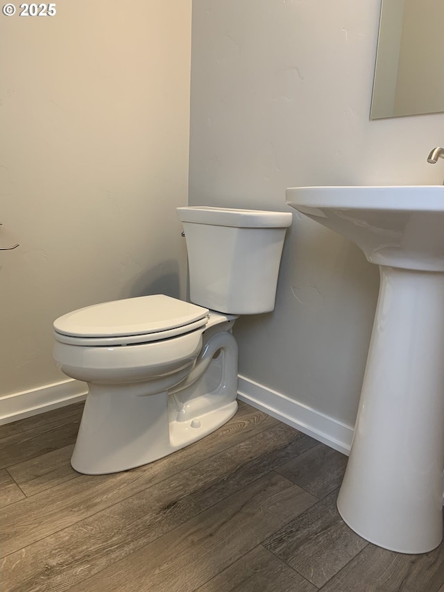 bathroom with baseboards, wood finished floors, and toilet