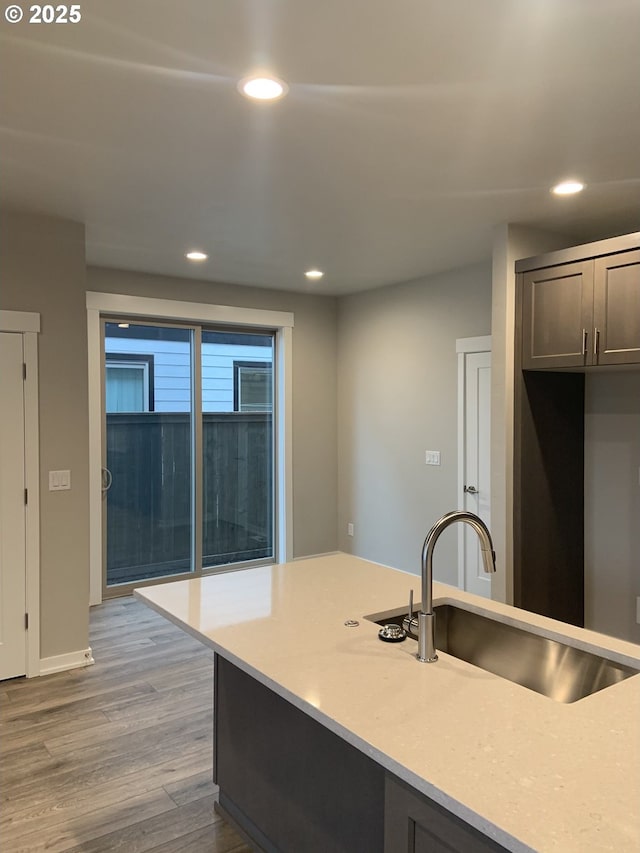 kitchen with a sink, light countertops, recessed lighting, and wood finished floors