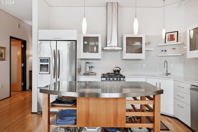 333 NW 9th Ave Unit 1205, Portland, OR 97209 - kitchen featuring stainless steel fridge, a sink, wall chimney range hood, white cabinetry, and backsplash