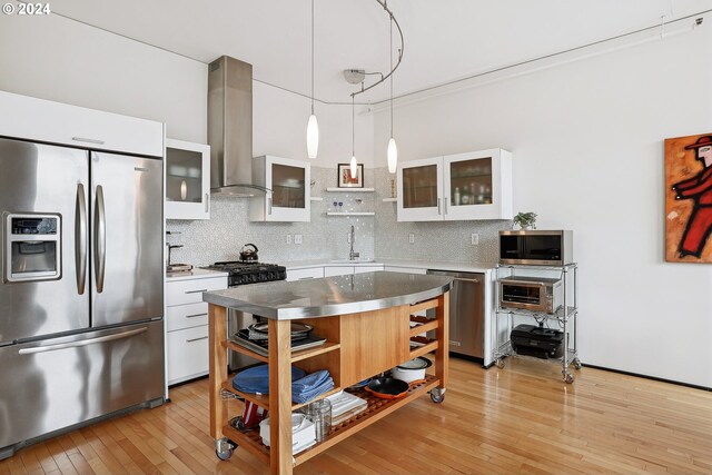333 NW 9th Ave Unit 1205, Portland, OR 97209 - kitchen with appliances with stainless steel finishes, stainless steel counters, wall chimney exhaust hood, and tasteful backsplash