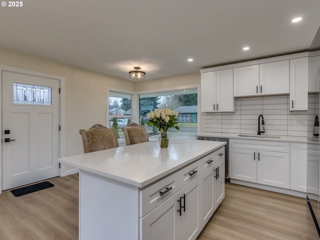 kitchen featuring tasteful backsplash, sink, white cabinetry, and light hardwood / wood-style floors