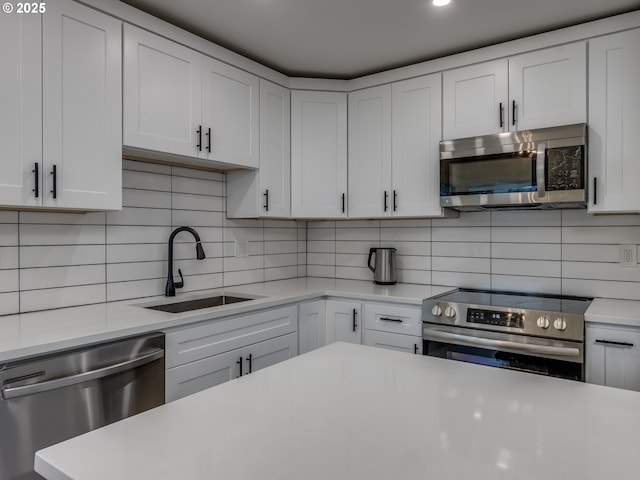 kitchen featuring decorative backsplash, sink, stainless steel appliances, and white cabinetry