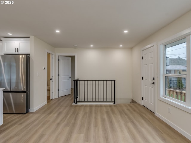 interior space featuring light wood-type flooring, white cabinets, and stainless steel fridge