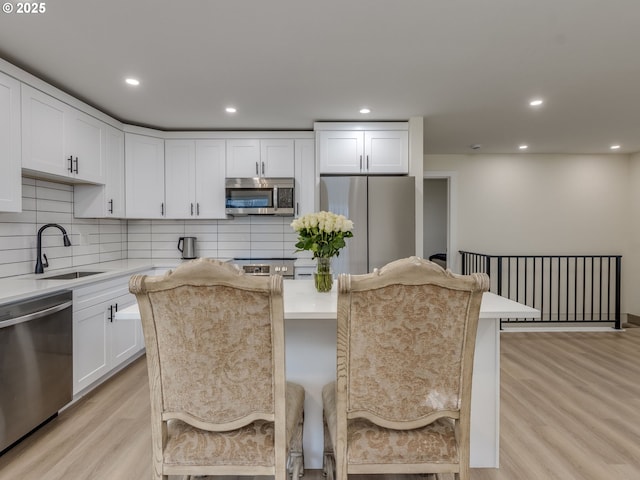 kitchen featuring stainless steel appliances, tasteful backsplash, a kitchen breakfast bar, a kitchen island, and white cabinets