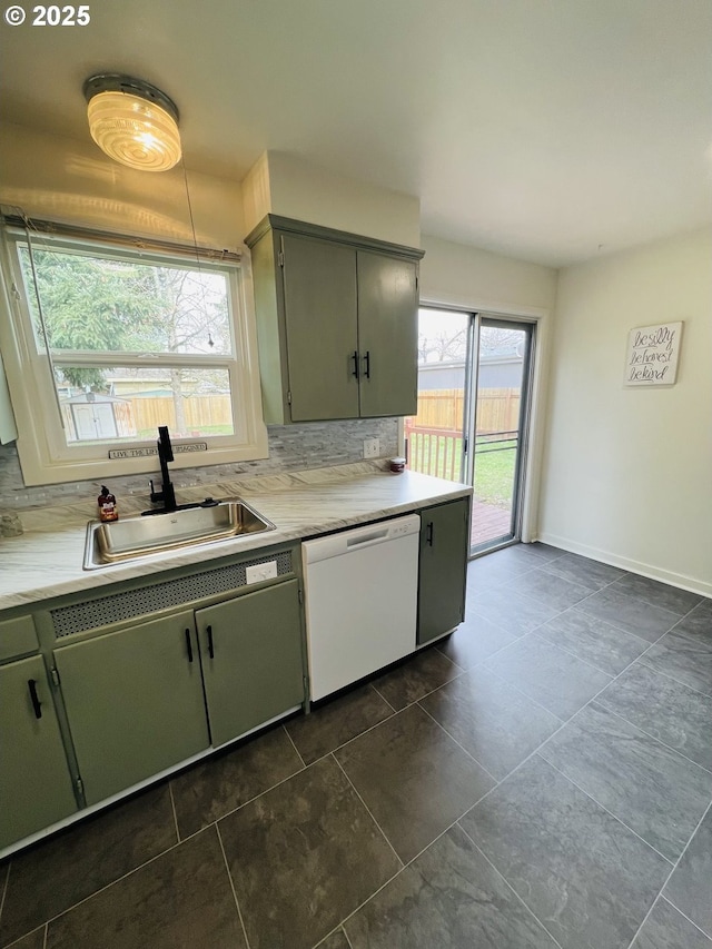 kitchen featuring baseboards, a sink, light countertops, dishwasher, and backsplash