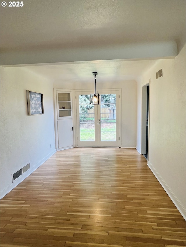 interior space featuring light wood-style floors, visible vents, french doors, and baseboards