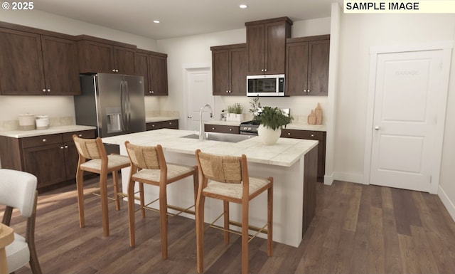 kitchen with a sink, dark wood-style floors, stainless steel appliances, dark brown cabinetry, and light countertops