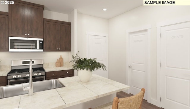 kitchen with stainless steel gas range oven, dark brown cabinetry, and recessed lighting