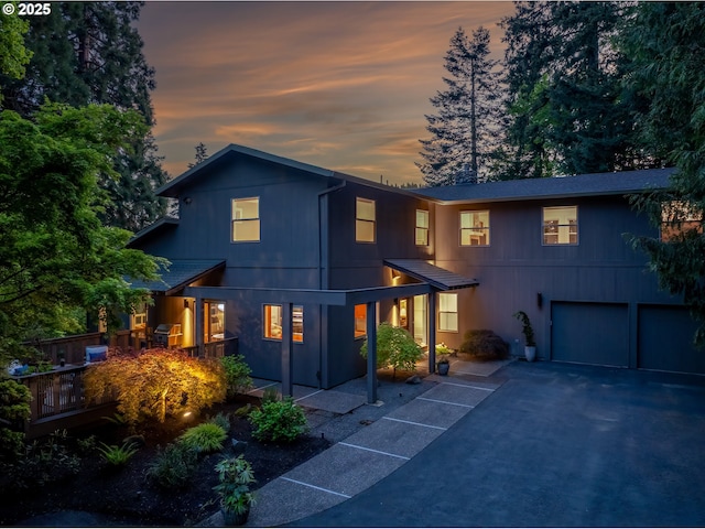 view of front facade featuring asphalt driveway, an attached garage, and a deck