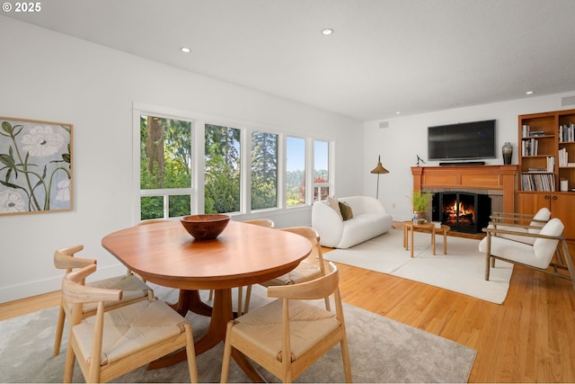 dining space featuring light wood finished floors, a brick fireplace, recessed lighting, and baseboards