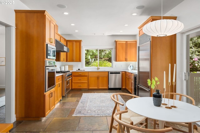 kitchen featuring built in appliances, stone tile flooring, light countertops, recessed lighting, and a sink