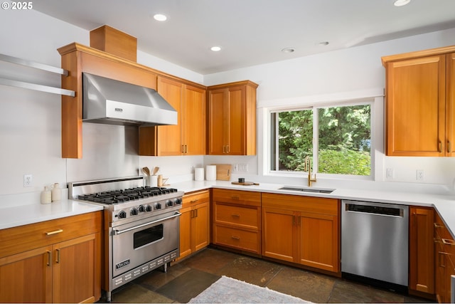 kitchen featuring stainless steel appliances, wall chimney range hood, a sink, dark stone finish flooring, and light countertops