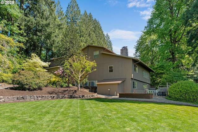 rear view of house with a chimney, a lawn, and a wooden deck