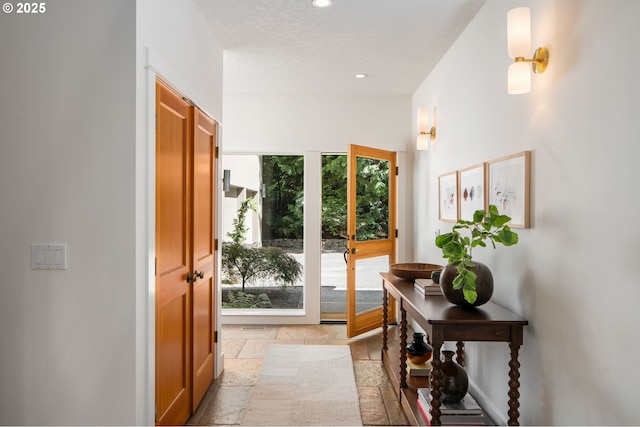 doorway to outside featuring stone tile floors, recessed lighting, and baseboards