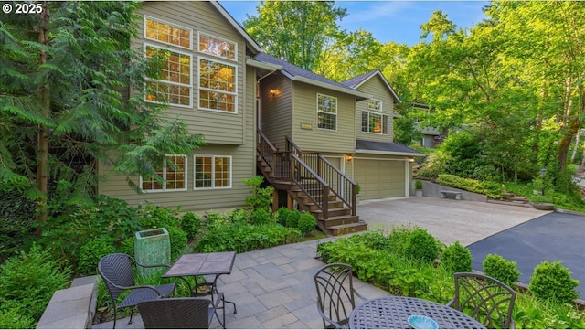 7445 SW Canyon Dr, Portland, OR 97225 - back of house with stairs, asphalt driveway, a garage, outdoor dining space, and a patio area