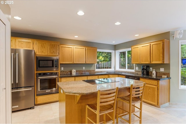 7445 SW Canyon Dr, Portland, OR 97225 - kitchen featuring stainless steel appliances, a center island, light stone counters, recessed lighting, and a kitchen bar