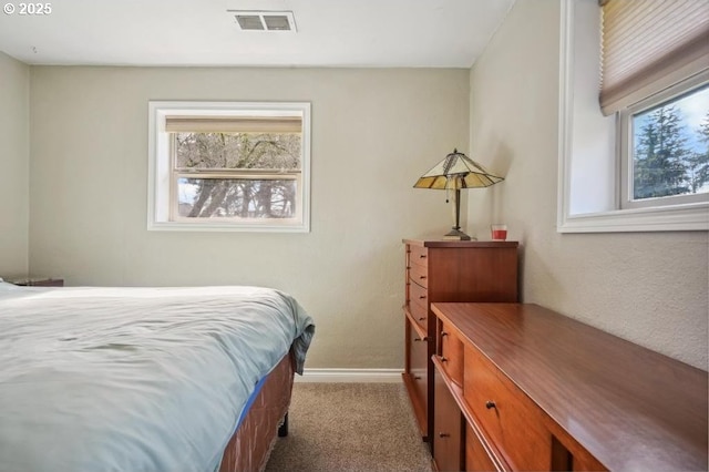 carpeted bedroom with multiple windows, baseboards, and visible vents