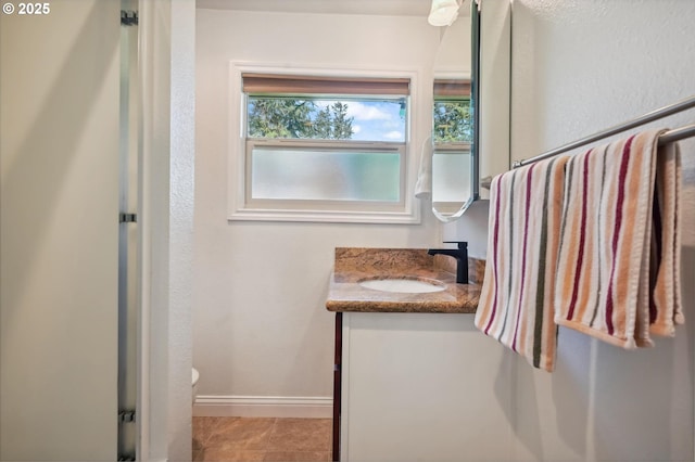 bathroom with toilet, tile patterned flooring, vanity, and baseboards