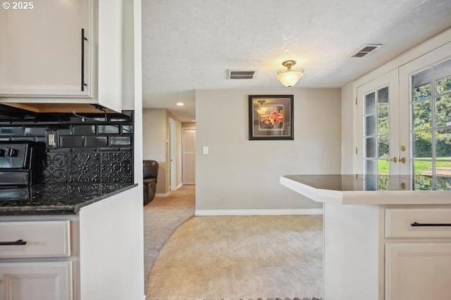 kitchen with white cabinetry, visible vents, french doors, and decorative backsplash