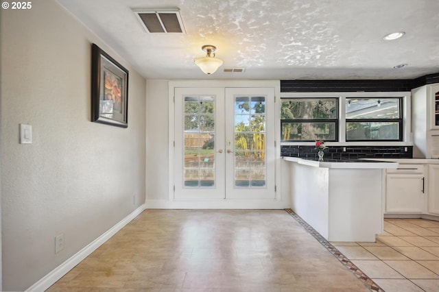 kitchen featuring visible vents, french doors, white cabinets, and baseboards